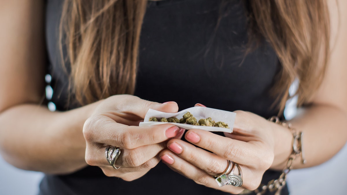 A marijuana joint that is rolled by hand nearby