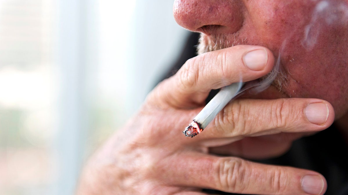 The largest Caucasian man approached his focused fingers while smoking a cigarette